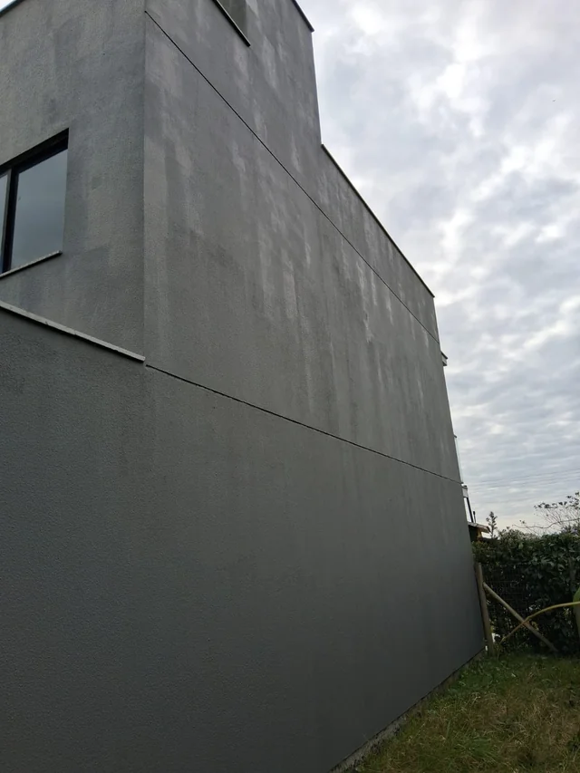 Parede externa cinza de uma residência, vista lateralmente.